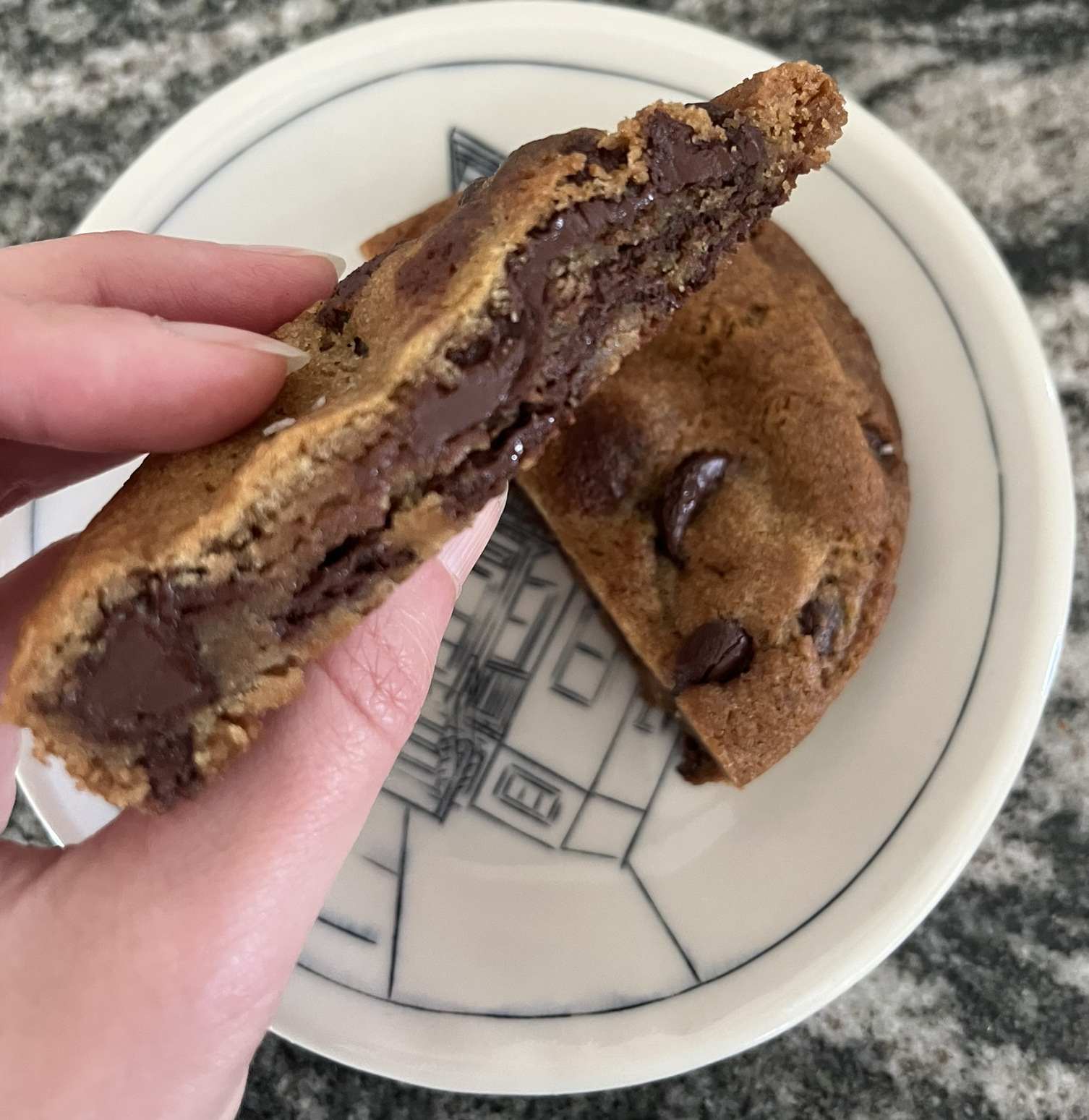 A cross section of a thick cookie that is mostly chocolate, with dough peaking through