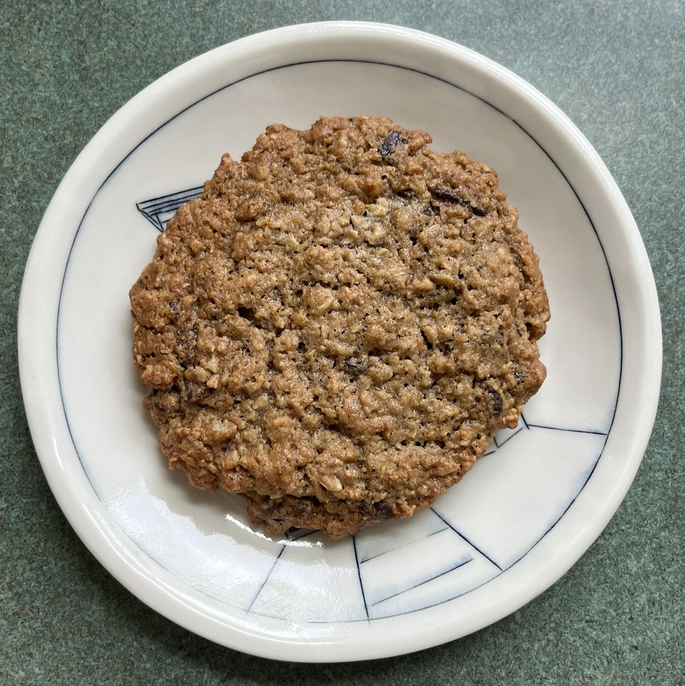 An oatmeal cookie with small bits of chocolate poking out of it. Don't be fooled- those aren't raisins, it's large chocolate piece that are beneath the surface