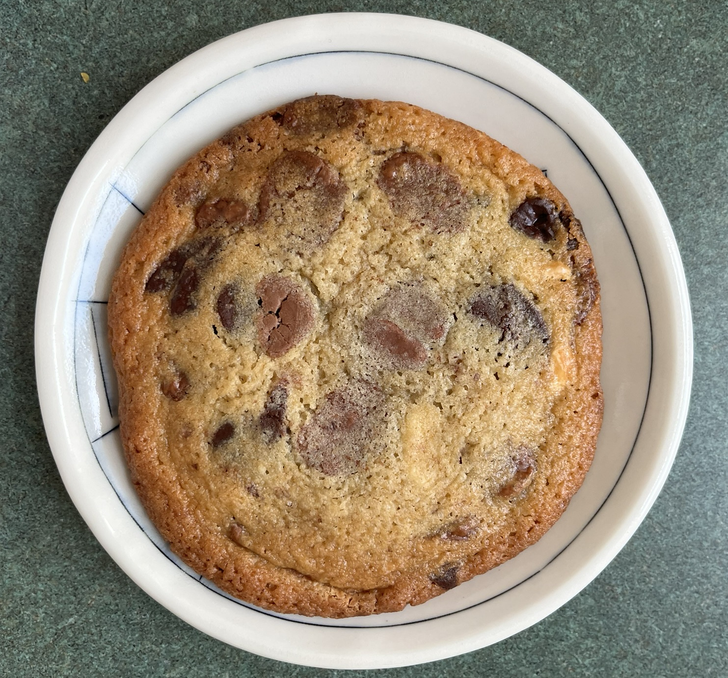 A cookie with a dark brown edge and large round chocolate chips in different colors